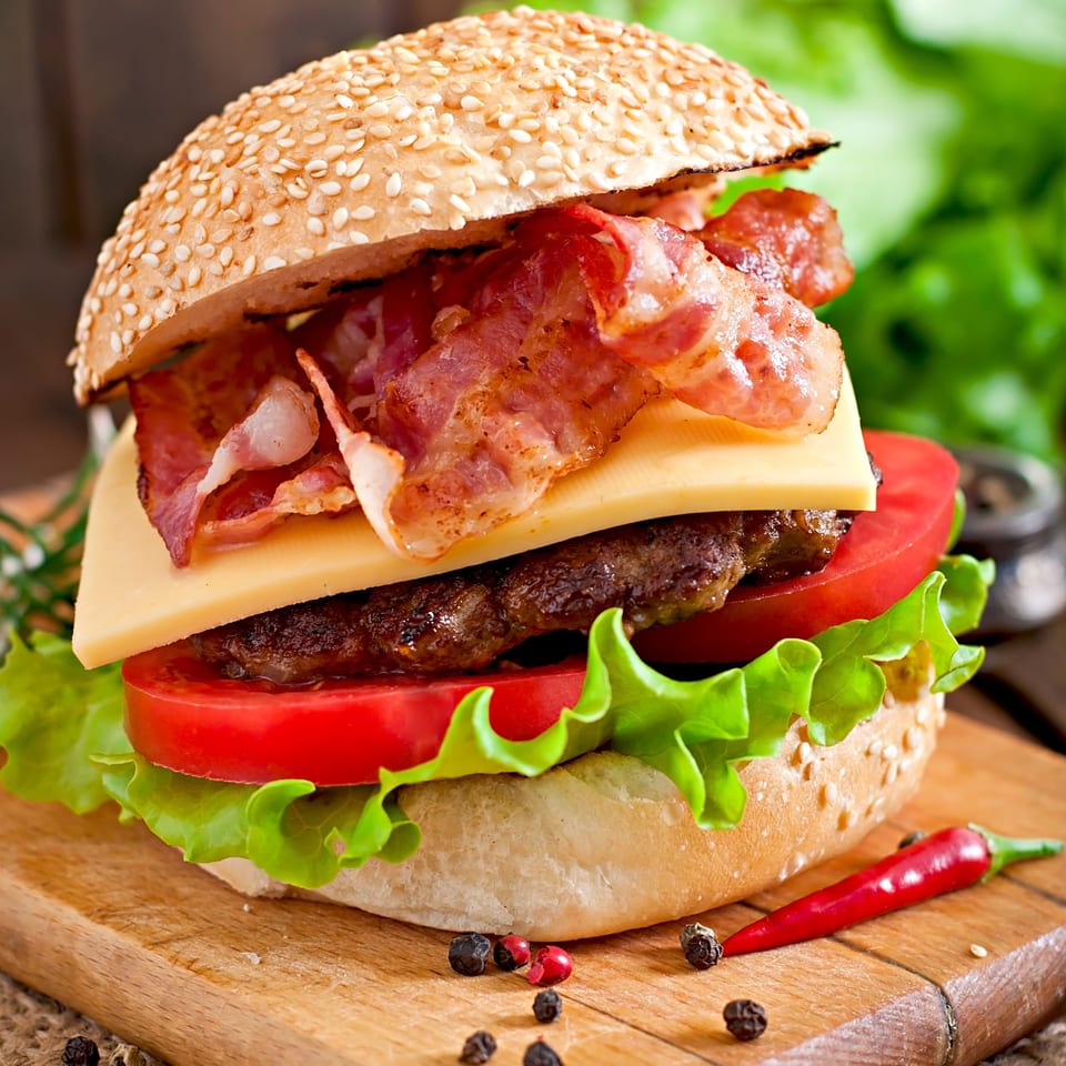 A Wolfy's diner bacon cheeseburger with lettuce and tomato on a sesame seed bun.