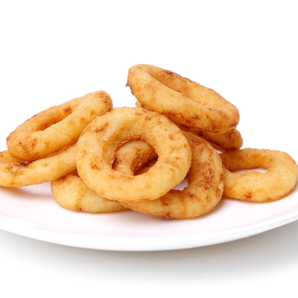 A close-up of a pile of golden-brown, crispy onion rings on a white plate.